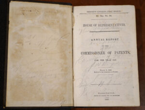 Old book, open to the title page where penciled in signatures of Confederate soldiers can be seen scrawled across the page.